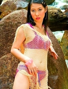 Olive Moon stands in her pink bra and she takes off her scarf. She sits down on a rock and feels on her hot body.