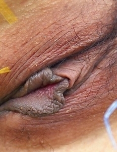 Jasmine Mookjai squats down and smiles at the camera. She shows how sexy she can be as she places her fingers close to her mouth.